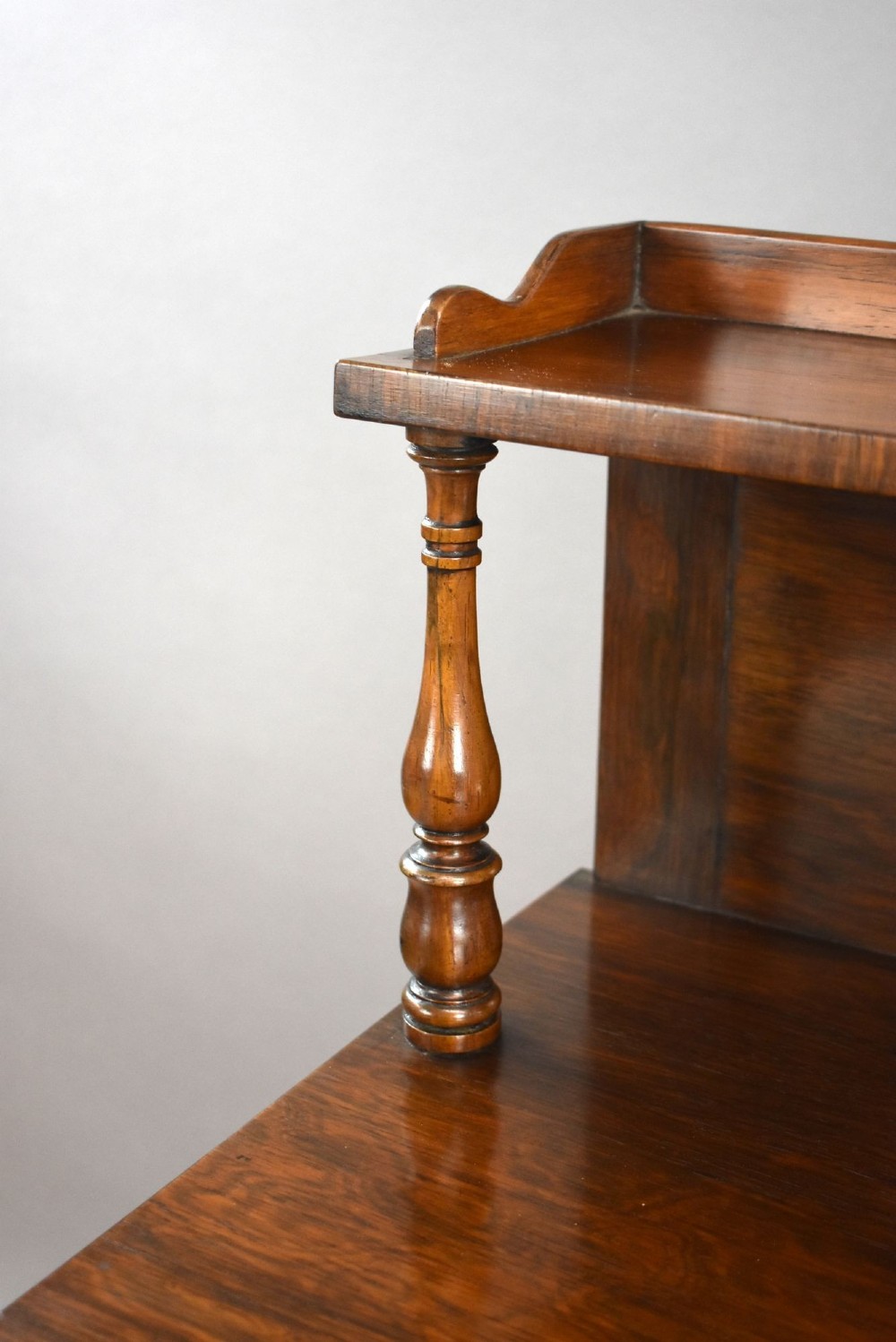 A Victorian dark rosewood chiffonier featuring an upper display shelf supported by turned pillars above lower cabinet doors fitted with pleated fabric panels. View VIII