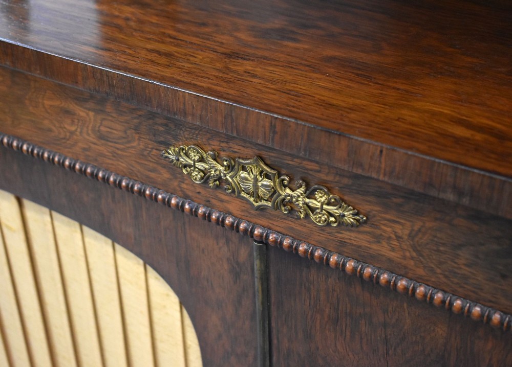A Victorian dark rosewood chiffonier featuring an upper display shelf supported by turned pillars above lower cabinet doors fitted with pleated fabric panels. View IX