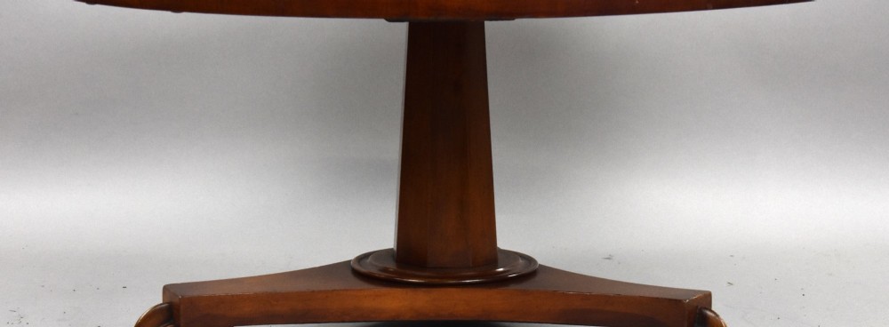 A low circular mahogany coffee table featuring a central pedestal stem on a tripartite platform base with scroll feet. View III