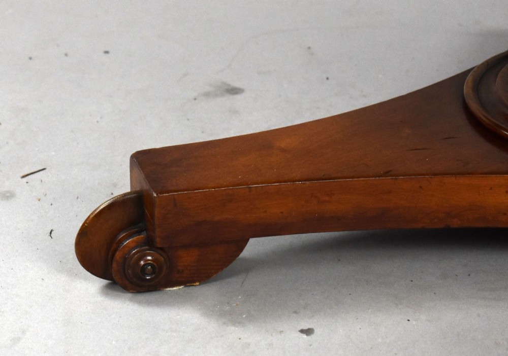 A low circular mahogany coffee table featuring a central pedestal stem on a tripartite platform base with scroll feet. View V