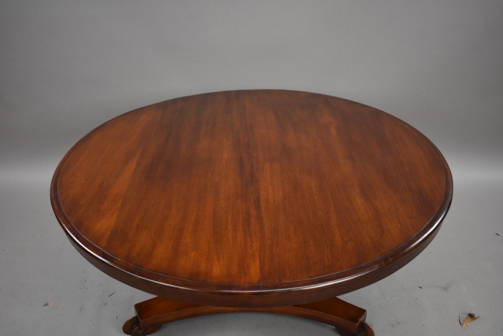 A low circular mahogany coffee table featuring a central pedestal stem on a tripartite platform base with scroll feet. View VI