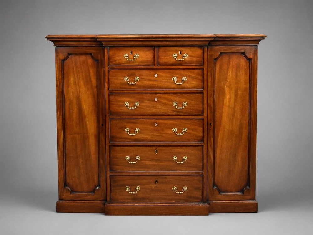 A Victorian mahogany breakfront sideboard featuring a central column of seven drawers flanked by two panelled cupboard doors with brass swan-neck handles.