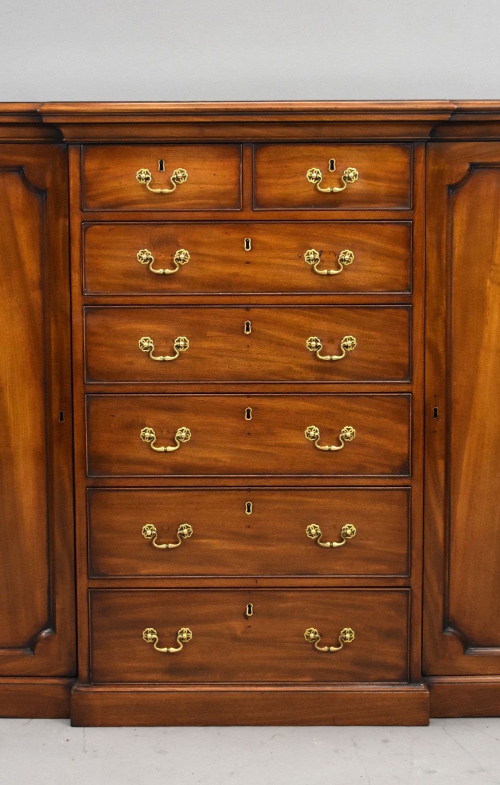 A Victorian mahogany breakfront sideboard featuring a central column of seven drawers flanked by two panelled cupboard doors with brass swan-neck handles. View III