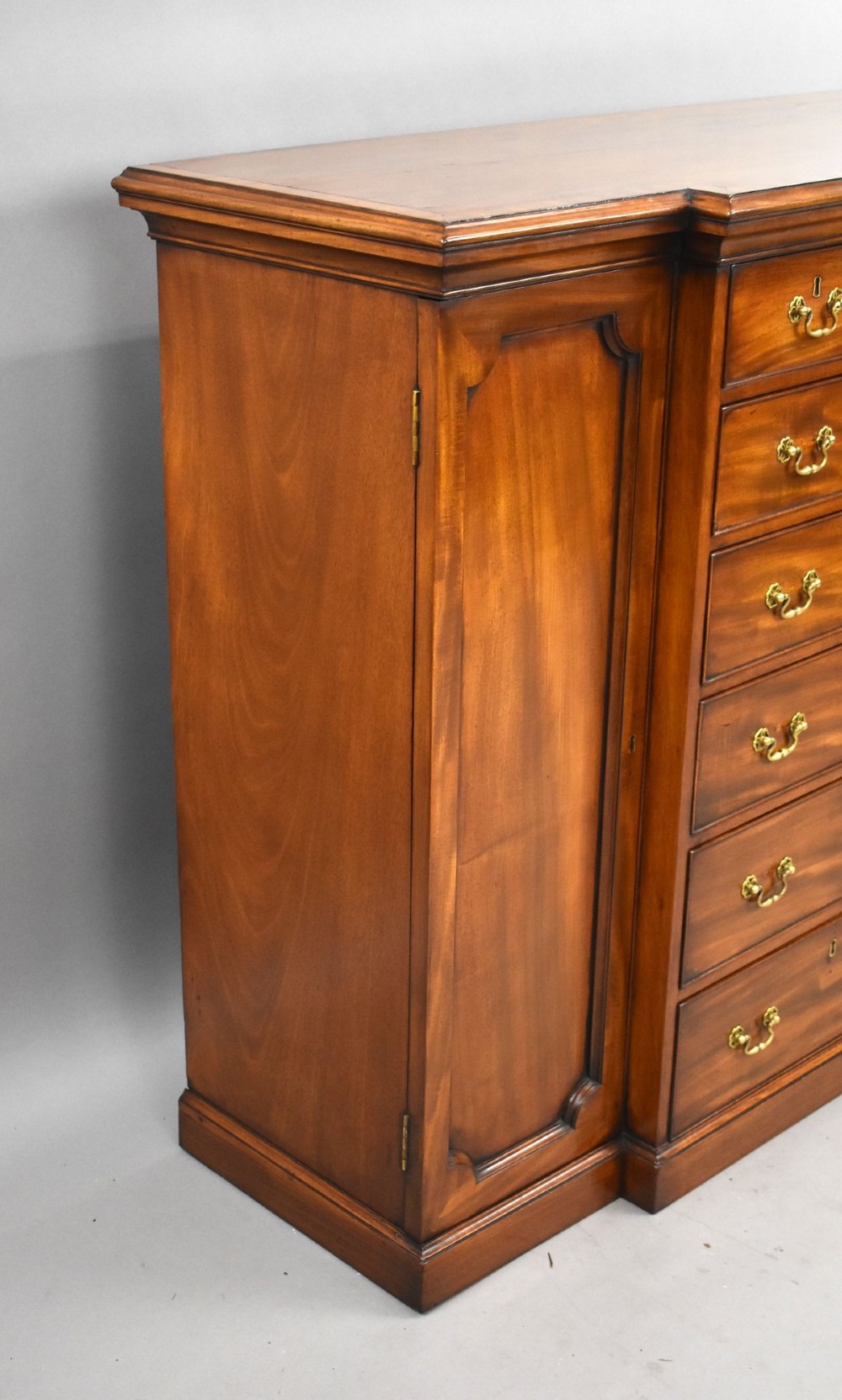 A Victorian mahogany breakfront sideboard featuring a central column of seven drawers flanked by two panelled cupboard doors with brass swan-neck handles. View V