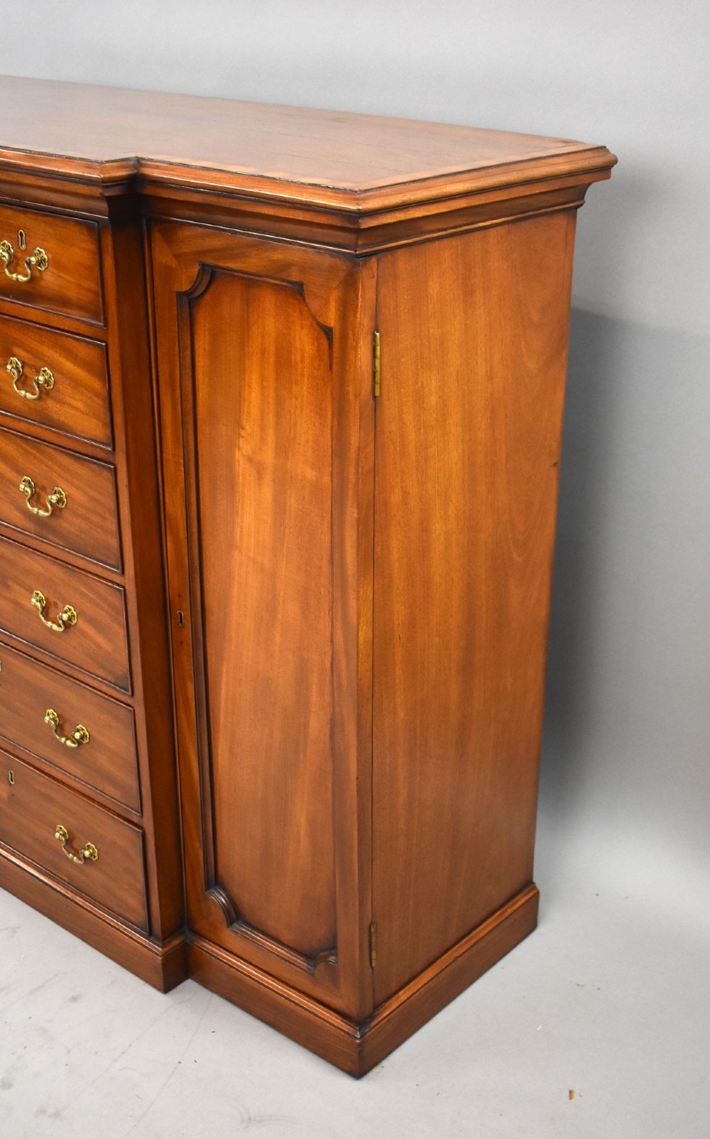 A Victorian mahogany breakfront sideboard featuring a central column of seven drawers flanked by two panelled cupboard doors with brass swan-neck handles. View VI