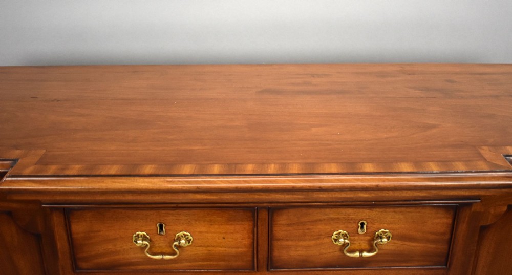 A Victorian mahogany breakfront sideboard featuring a central column of seven drawers flanked by two panelled cupboard doors with brass swan-neck handles. View IX