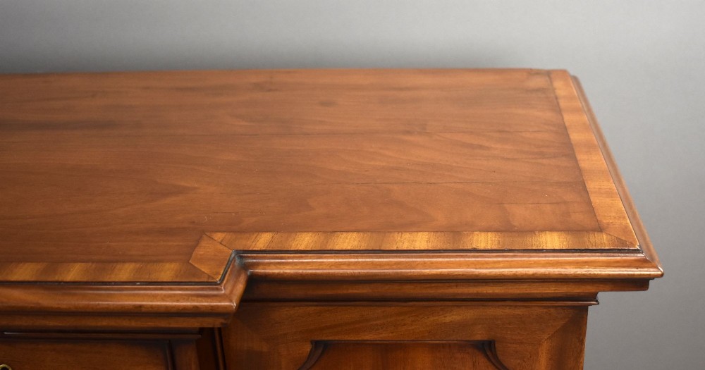 A Victorian mahogany breakfront sideboard featuring a central column of seven drawers flanked by two panelled cupboard doors with brass swan-neck handles. View X