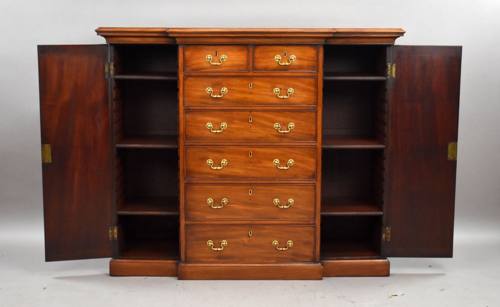 A Victorian mahogany breakfront sideboard featuring a central column of seven drawers flanked by two panelled cupboard doors with brass swan-neck handles. View XI