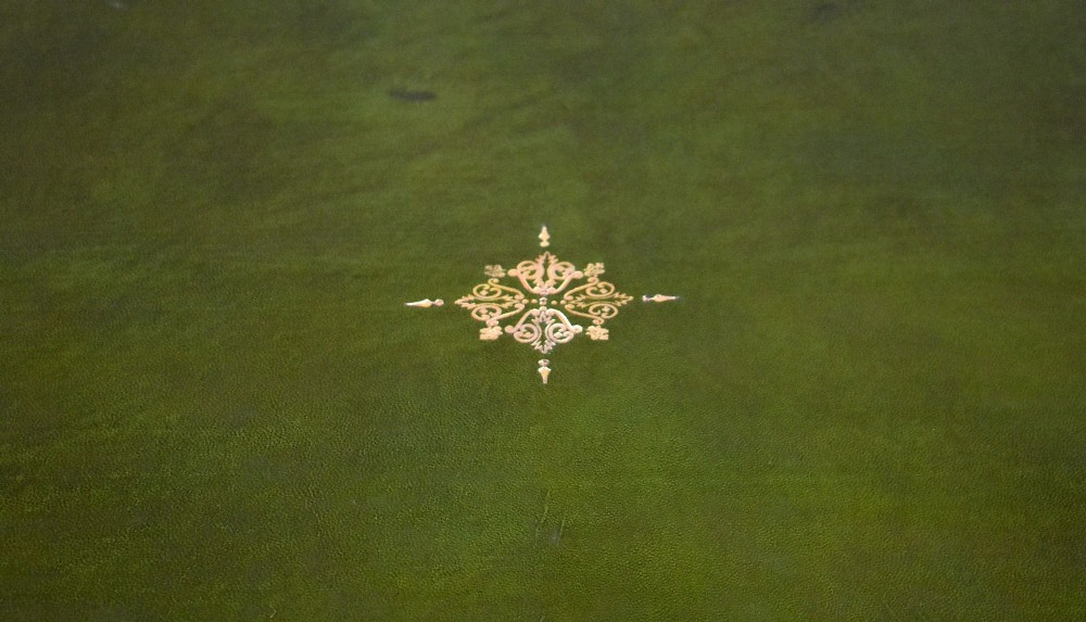 A dark oak Victorian writing desk featuring a green leather inset top with gold tooling, detailed lion mask carvings on the drawer fronts, and scroll corbels. View XII