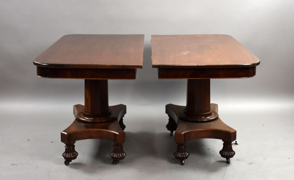 A pair of antique William IV mahogany console tables featuring rounded rectangular tops, central cylindrical pedestals, concave plinth bases, and carved lobed feet on brass castors. View III