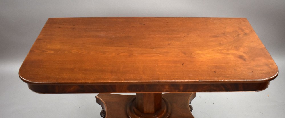 A pair of antique William IV mahogany console tables featuring rounded rectangular tops, central cylindrical pedestals, concave plinth bases, and carved lobed feet on brass castors. View VI