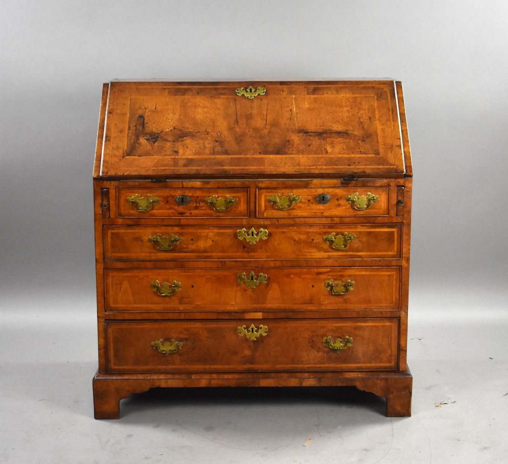 A George I figured walnut bureau with a sloping fall-front, brass drop handles, keyhole escutcheons, and bracket feet. View III