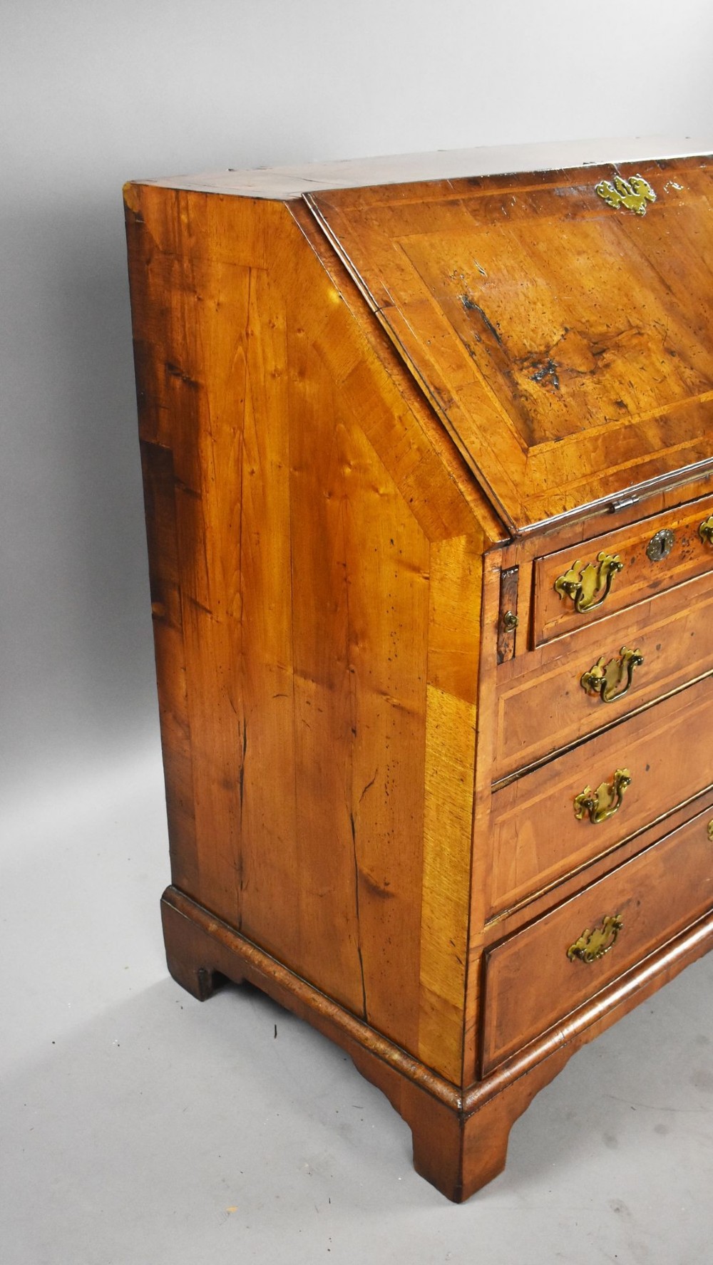 A George I figured walnut bureau with a sloping fall-front, brass drop handles, keyhole escutcheons, and bracket feet. View IV