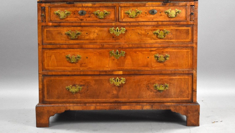 A George I figured walnut bureau with a sloping fall-front, brass drop handles, keyhole escutcheons, and bracket feet. View VIII