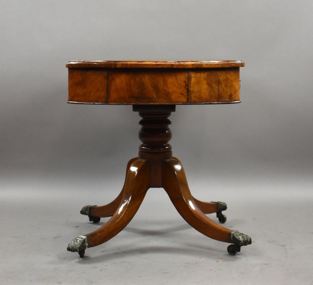 A Victorian burr walnut writing table featuring a green leather inset top, frieze drawers, and a central turned pedestal on splayed legs with brass lion paw castors. View III