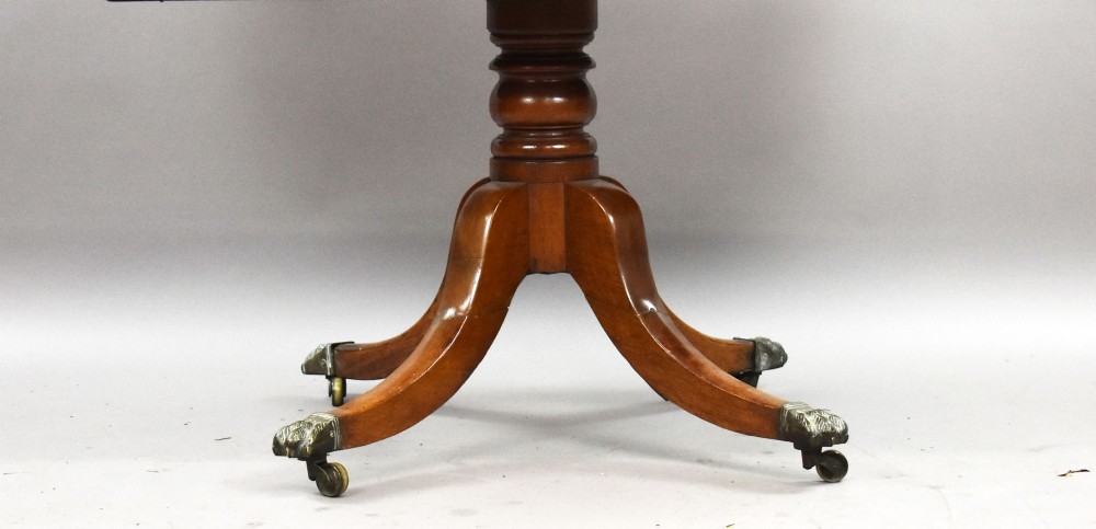 A Victorian burr walnut writing table featuring a green leather inset top, frieze drawers, and a central turned pedestal on splayed legs with brass lion paw castors. View VIII