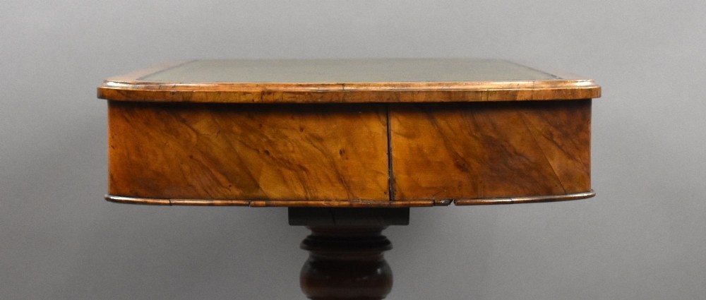 A Victorian burr walnut writing table featuring a green leather inset top, frieze drawers, and a central turned pedestal on splayed legs with brass lion paw castors. View XI