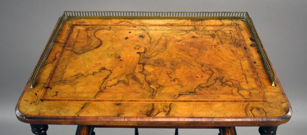 A Victorian burr walnut Canterbury featuring a top tier with a brass gallery rail, turned spindle columns, open partitions, a single inlaid drawer, and turned legs on brass castors. View V