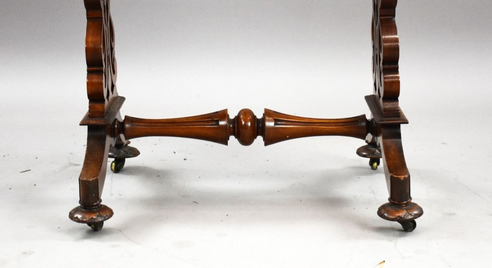 A Victorian mahogany work table featuring a fretwork gallery top, a single lockable drawer, a pleated cream fabric drop well, and carved scroll legs with brass castors. View VII