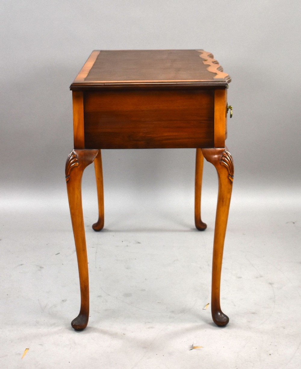 A Queen Anne style walnut writing desk featuring a brown leather inset top, serpentine front drawers with brass handles, and carved cabriole legs. View III