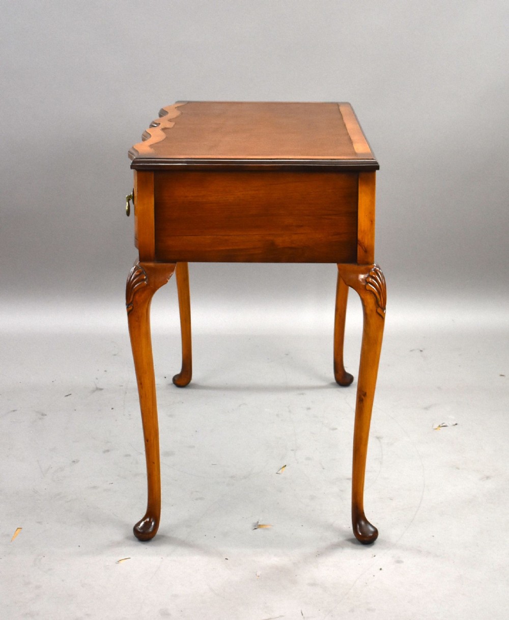 A Queen Anne style walnut writing desk featuring a brown leather inset top, serpentine front drawers with brass handles, and carved cabriole legs. View V