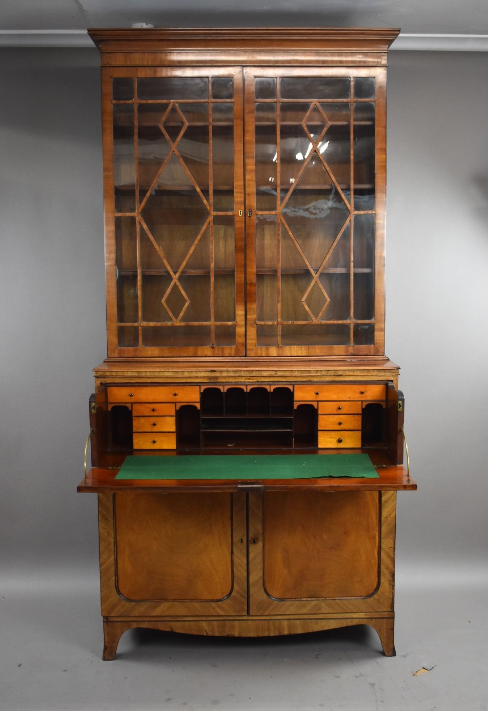 An antique mahogany secretaire bookcase featuring a glazed upper display cabinet with diamond astragal glazing bars above a lower chest and double cupboard base. View III