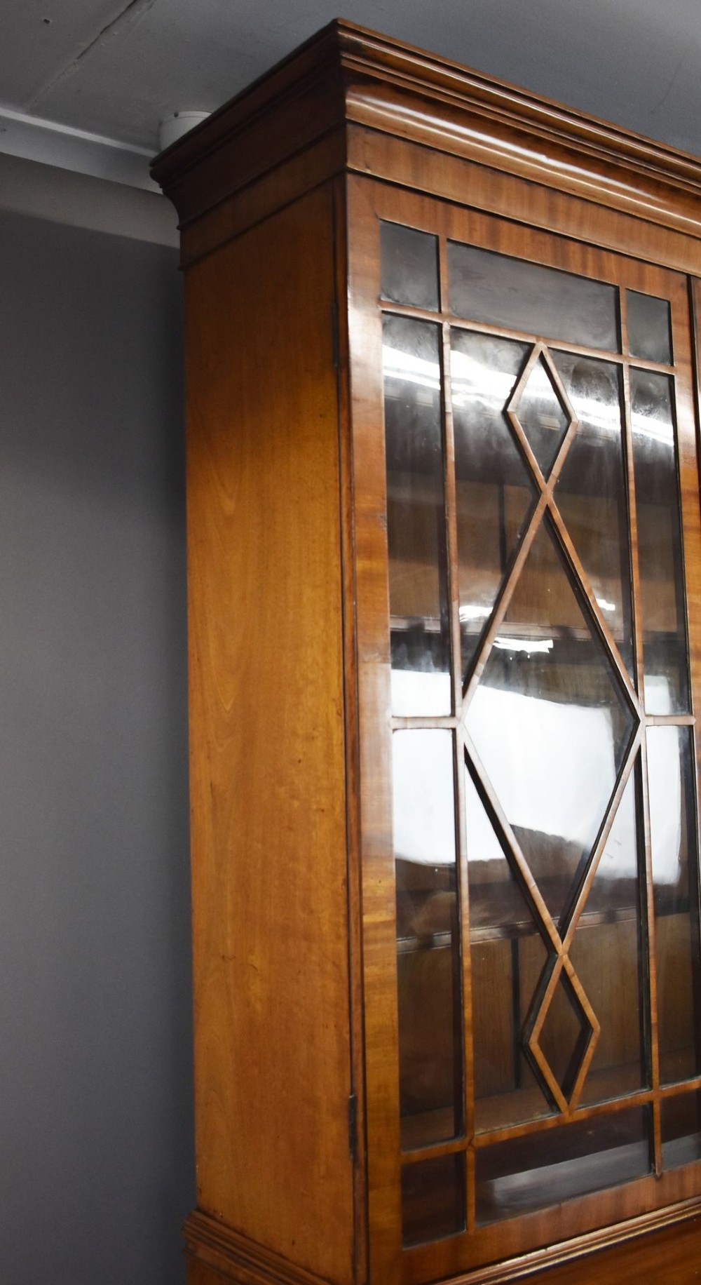 An antique mahogany secretaire bookcase featuring a glazed upper display cabinet with diamond astragal glazing bars above a lower chest and double cupboard base. View IV