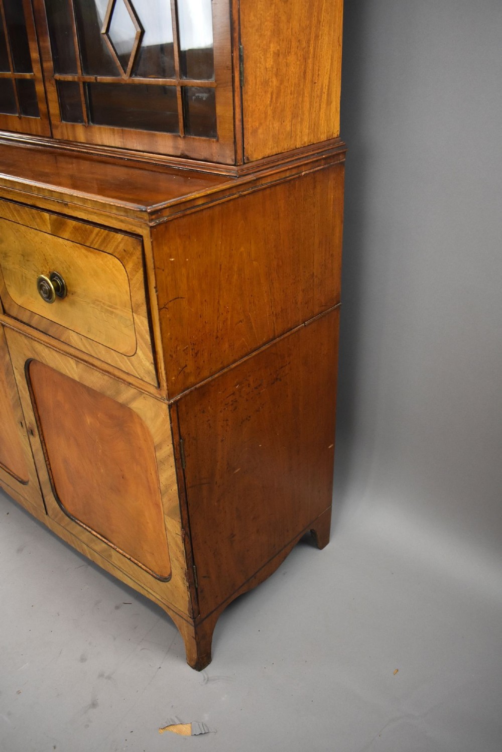 An antique mahogany secretaire bookcase featuring a glazed upper display cabinet with diamond astragal glazing bars above a lower chest and double cupboard base. View VII