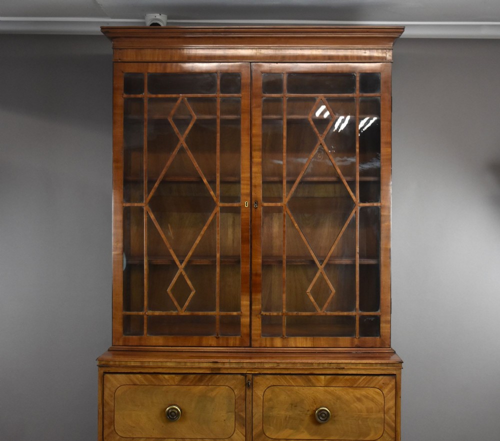 An antique mahogany secretaire bookcase featuring a glazed upper display cabinet with diamond astragal glazing bars above a lower chest and double cupboard base. View IX
