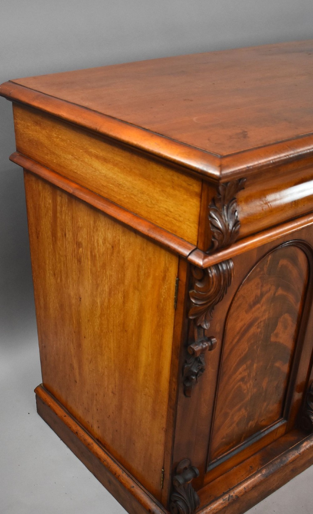 A nineteenth-century Victorian flame mahogany four-door sideboard featuring arched door panels, carved pilaster corbels, and a wide plinth base. View VIII