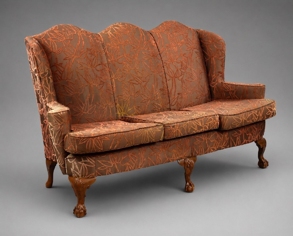 A Queen Anne style three-seat sofa featuring terracotta leaf-patterned upholstery, a triple-arched backrest, and carved walnut cabriole legs with ball-and-claw feet.