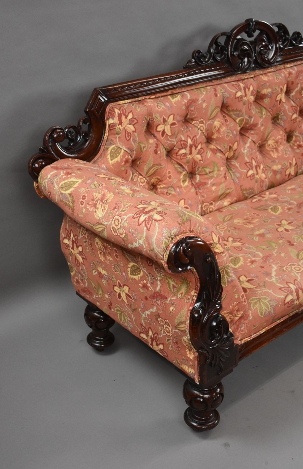 Victorian mahogany settee featuring carved scroll cresting along the top rail, button-tufted floral fabric upholstery, rolled armrests, and turned wooden front legs. View II