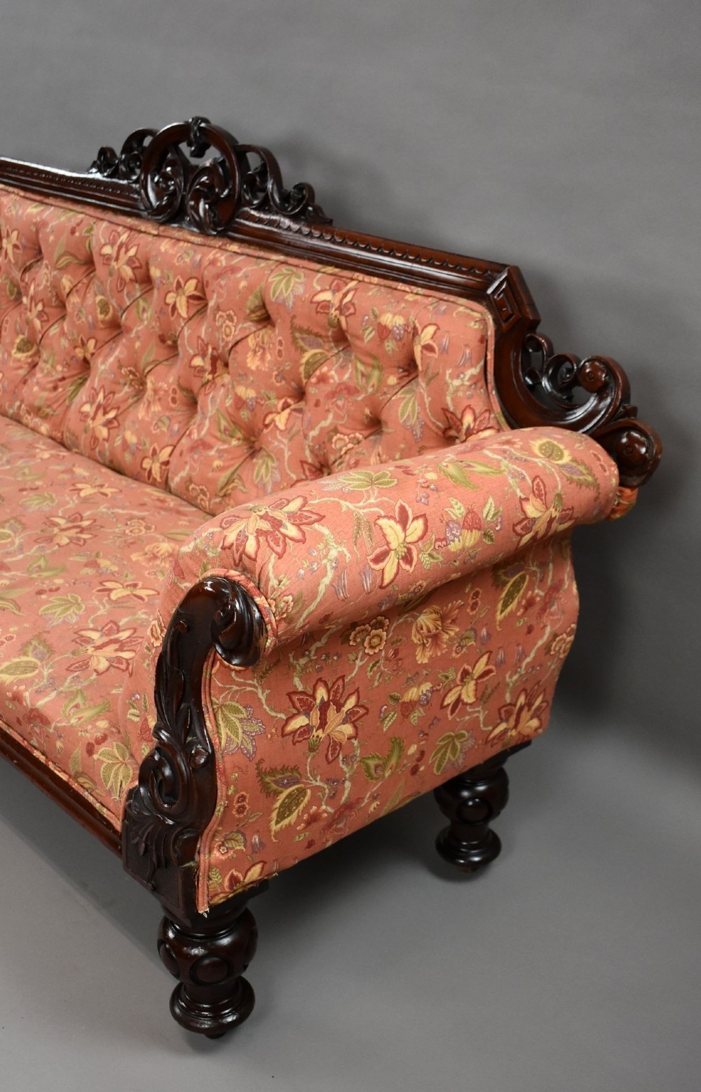 Victorian mahogany settee featuring carved scroll cresting along the top rail, button-tufted floral fabric upholstery, rolled armrests, and turned wooden front legs. View III