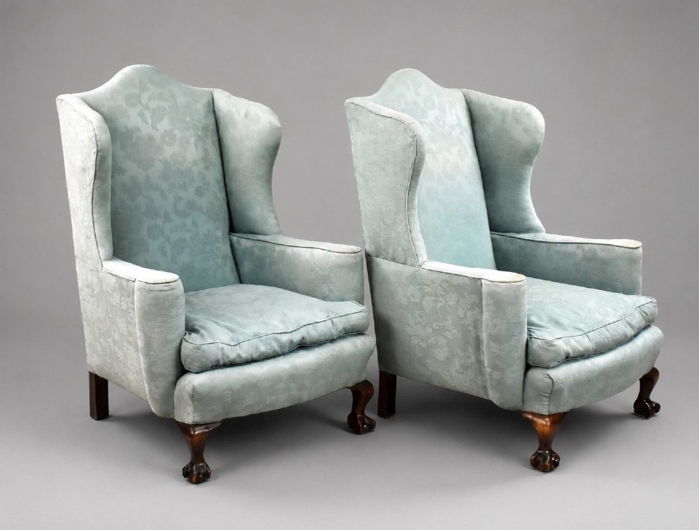A pair of antique wingback armchairs upholstered in duck egg blue damask fabric with carved cabriole legs and ball-and-claw feet.