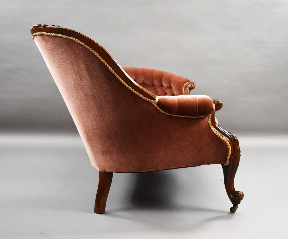 A Victorian carved walnut chaise longue upholstered in deep-buttoned rose pink velvet with cabriole legs on brass castors. View VI