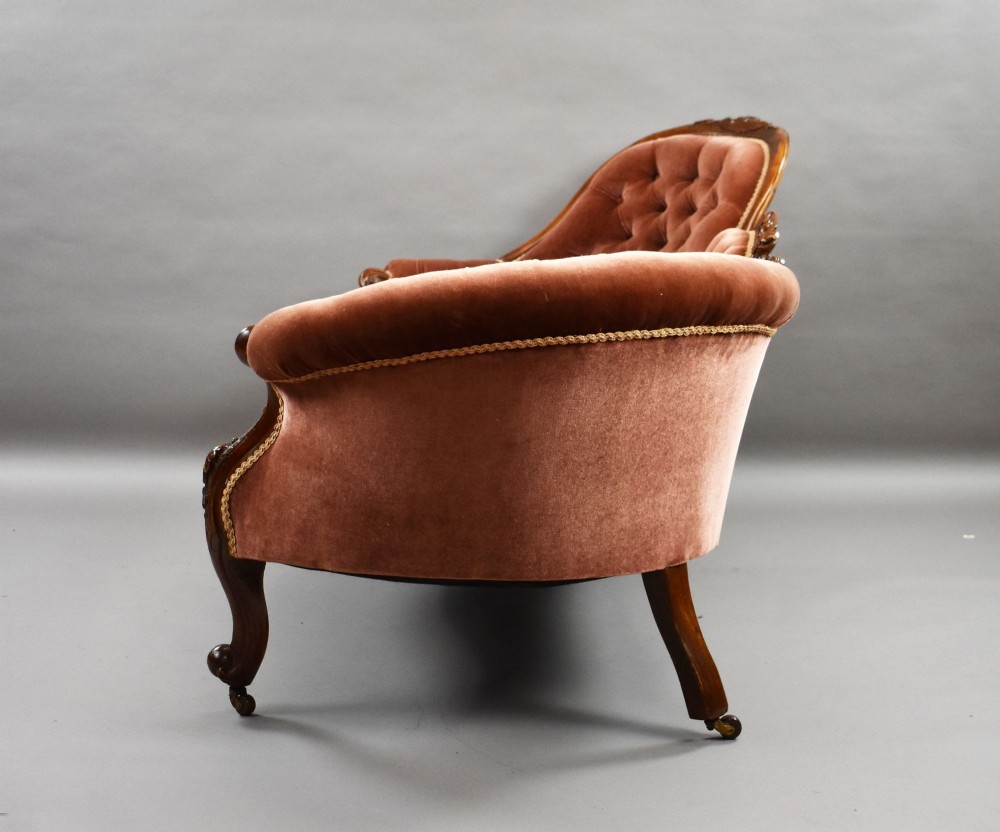A Victorian carved walnut chaise longue upholstered in deep-buttoned rose pink velvet with cabriole legs on brass castors. View VIII