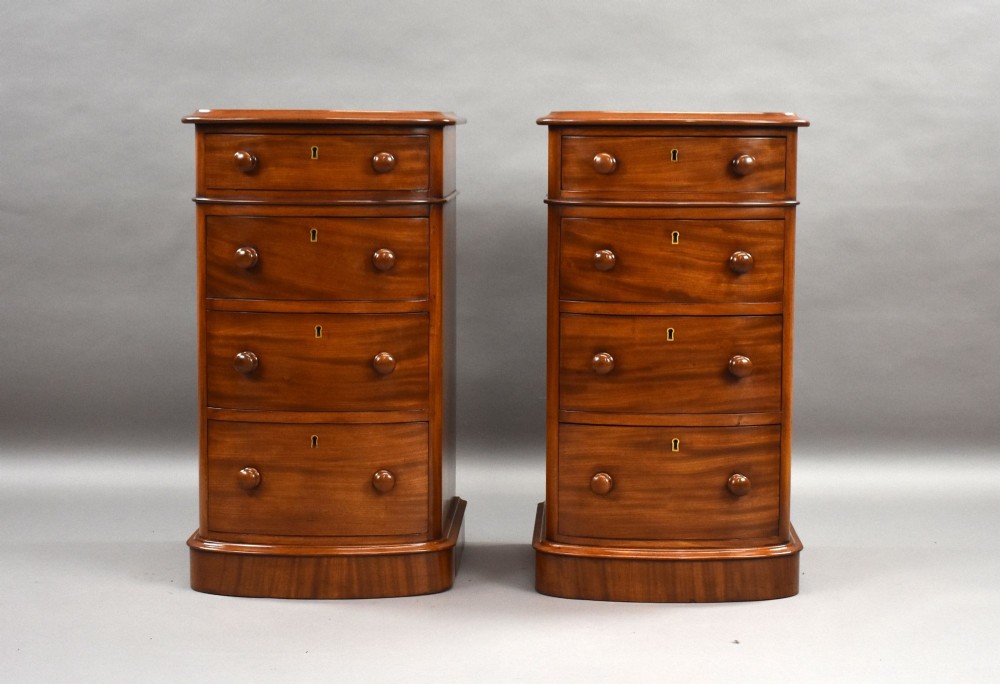 A matching pair of four-drawer Victorian mahogany bedside chests featuring curved fronted drawers, turned wooden handles, and plinth bases. View II