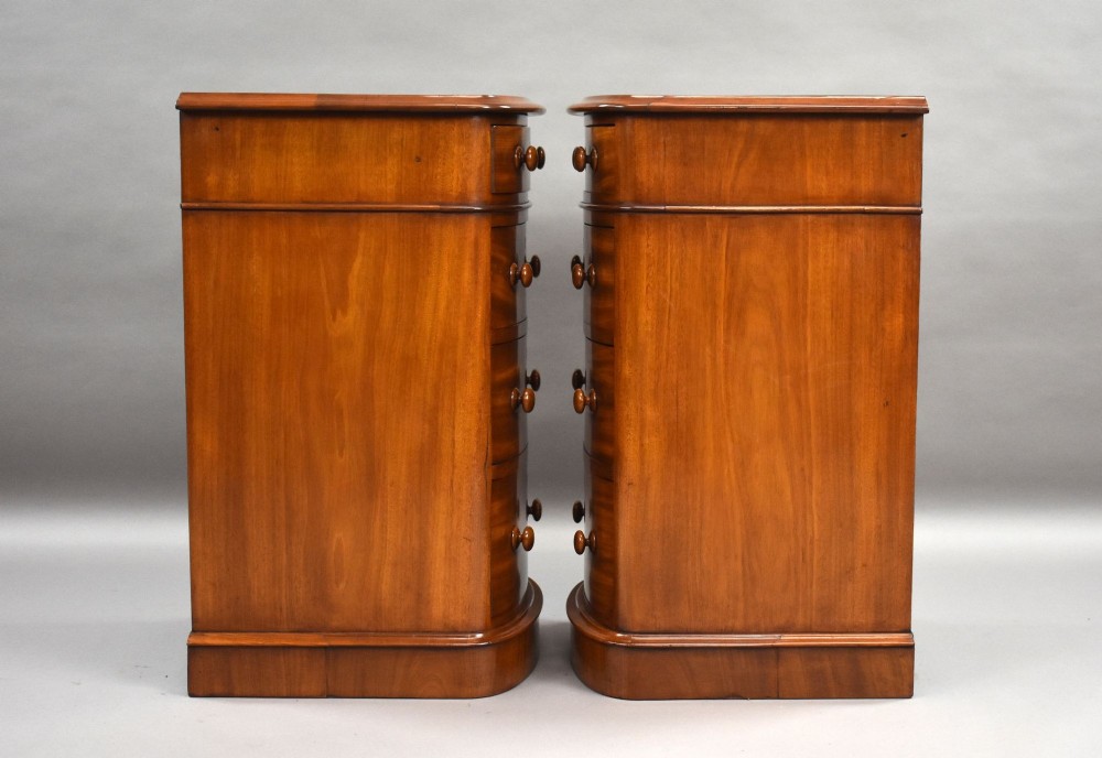 A matching pair of four-drawer Victorian mahogany bedside chests featuring curved fronted drawers, turned wooden handles, and plinth bases. View IV