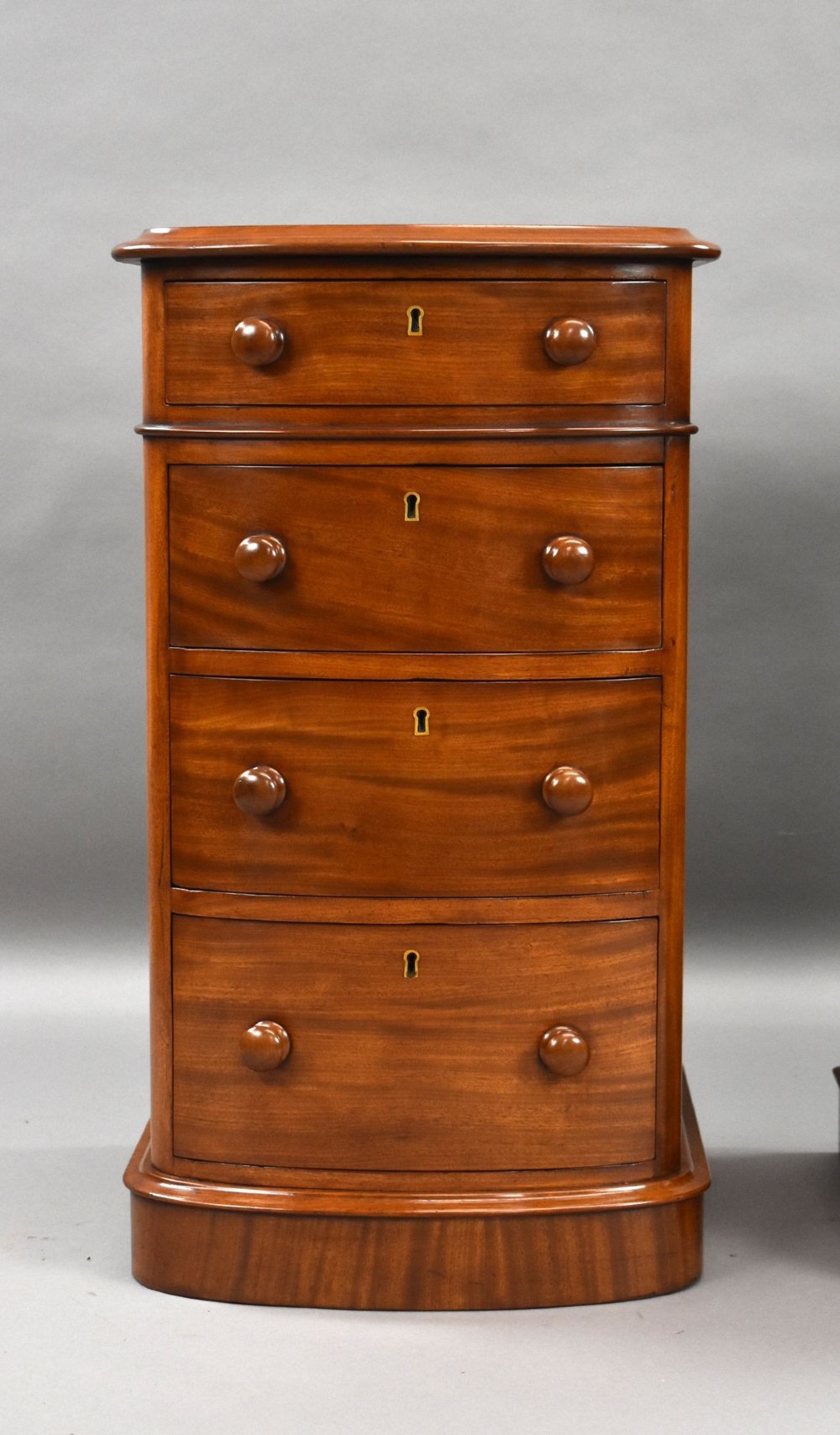 A matching pair of four-drawer Victorian mahogany bedside chests featuring curved fronted drawers, turned wooden handles, and plinth bases. View VII