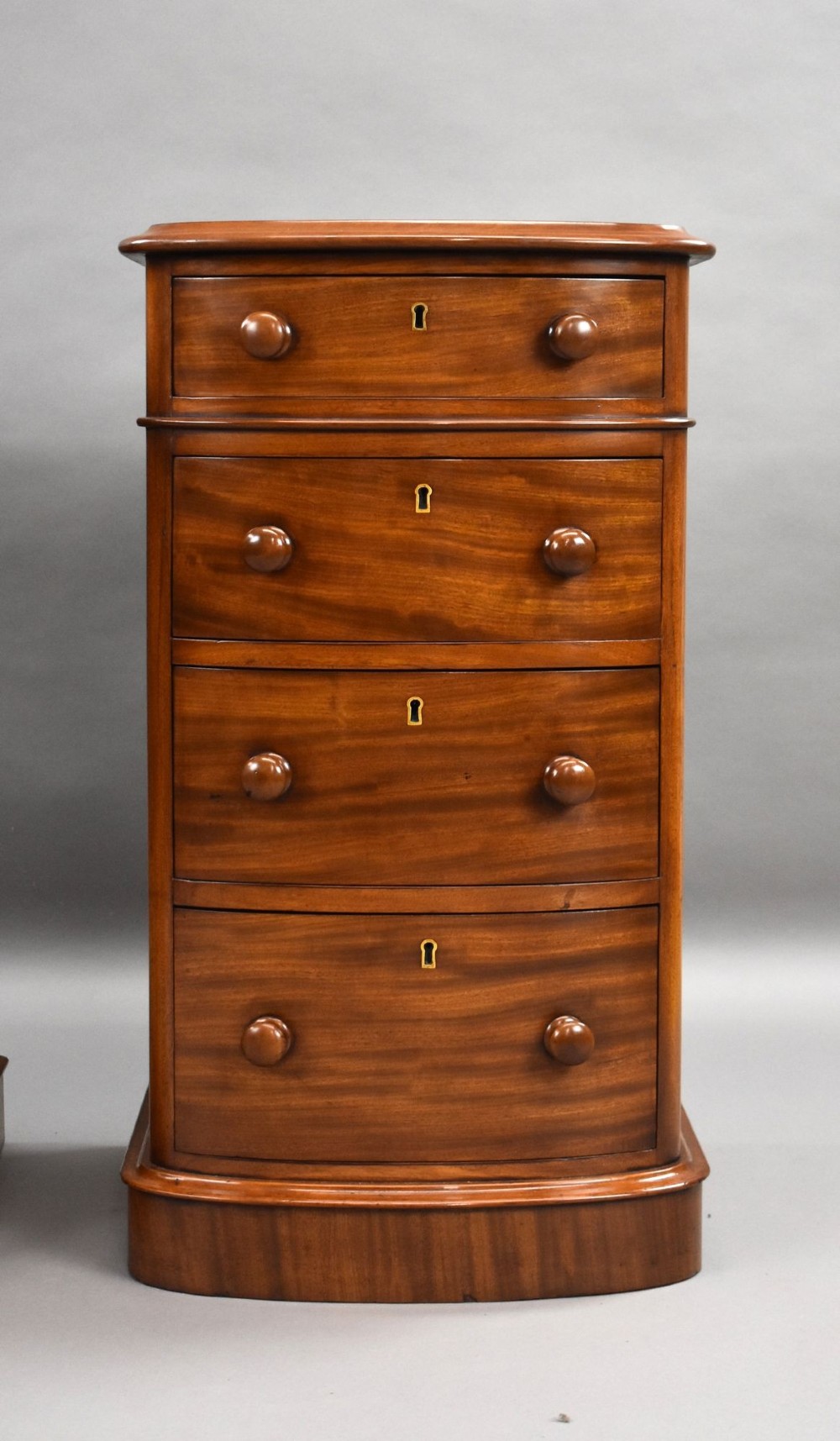 A matching pair of four-drawer Victorian mahogany bedside chests featuring curved fronted drawers, turned wooden handles, and plinth bases. View VIII