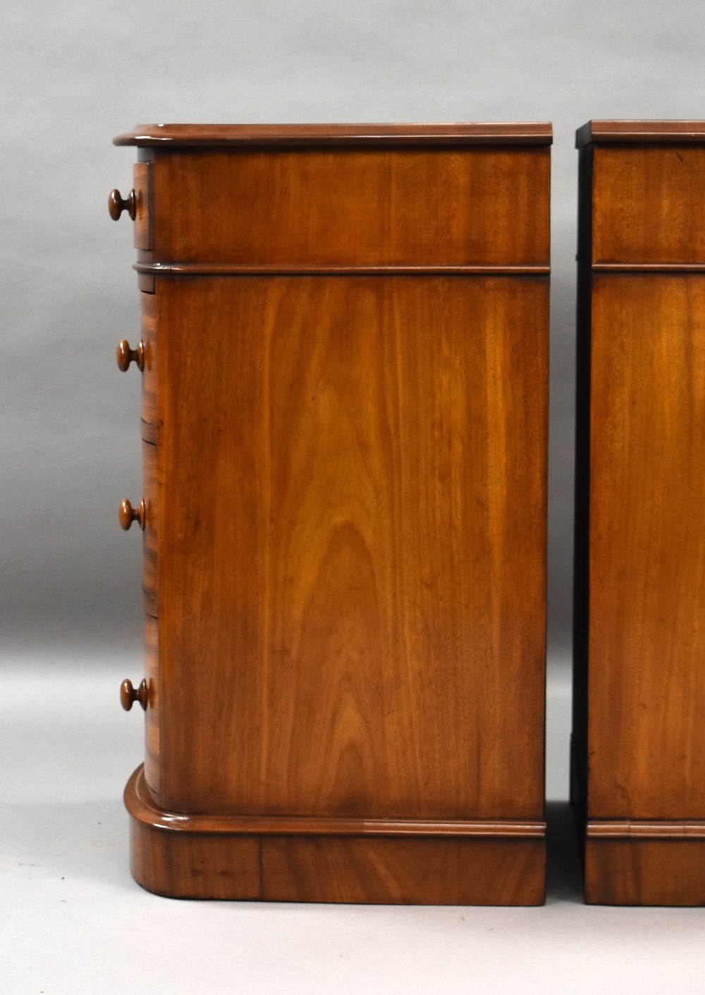 A matching pair of four-drawer Victorian mahogany bedside chests featuring curved fronted drawers, turned wooden handles, and plinth bases. View IX