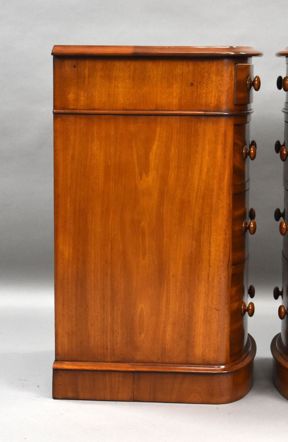 A matching pair of four-drawer Victorian mahogany bedside chests featuring curved fronted drawers, turned wooden handles, and plinth bases. View XI