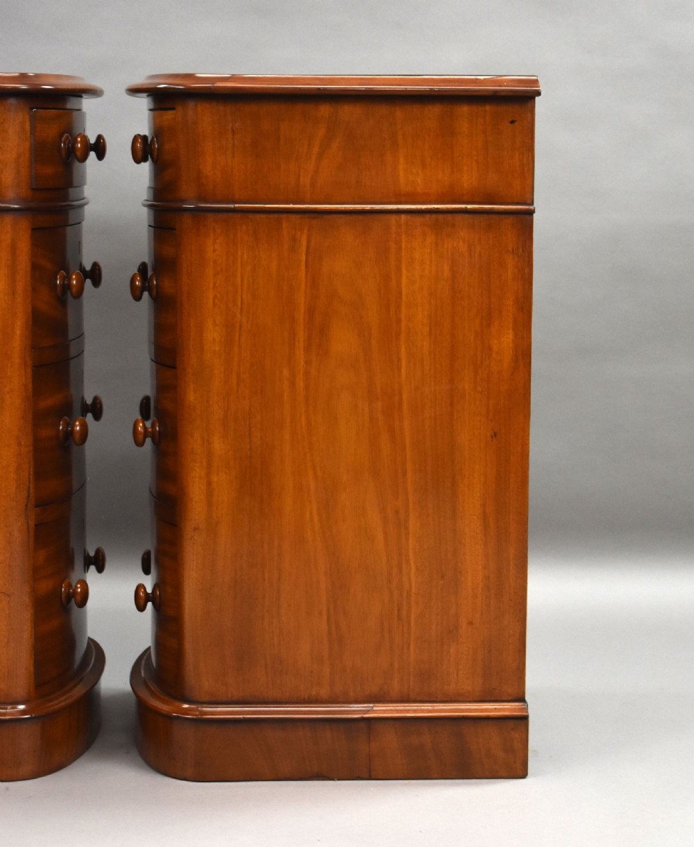 A matching pair of four-drawer Victorian mahogany bedside chests featuring curved fronted drawers, turned wooden handles, and plinth bases. View XII