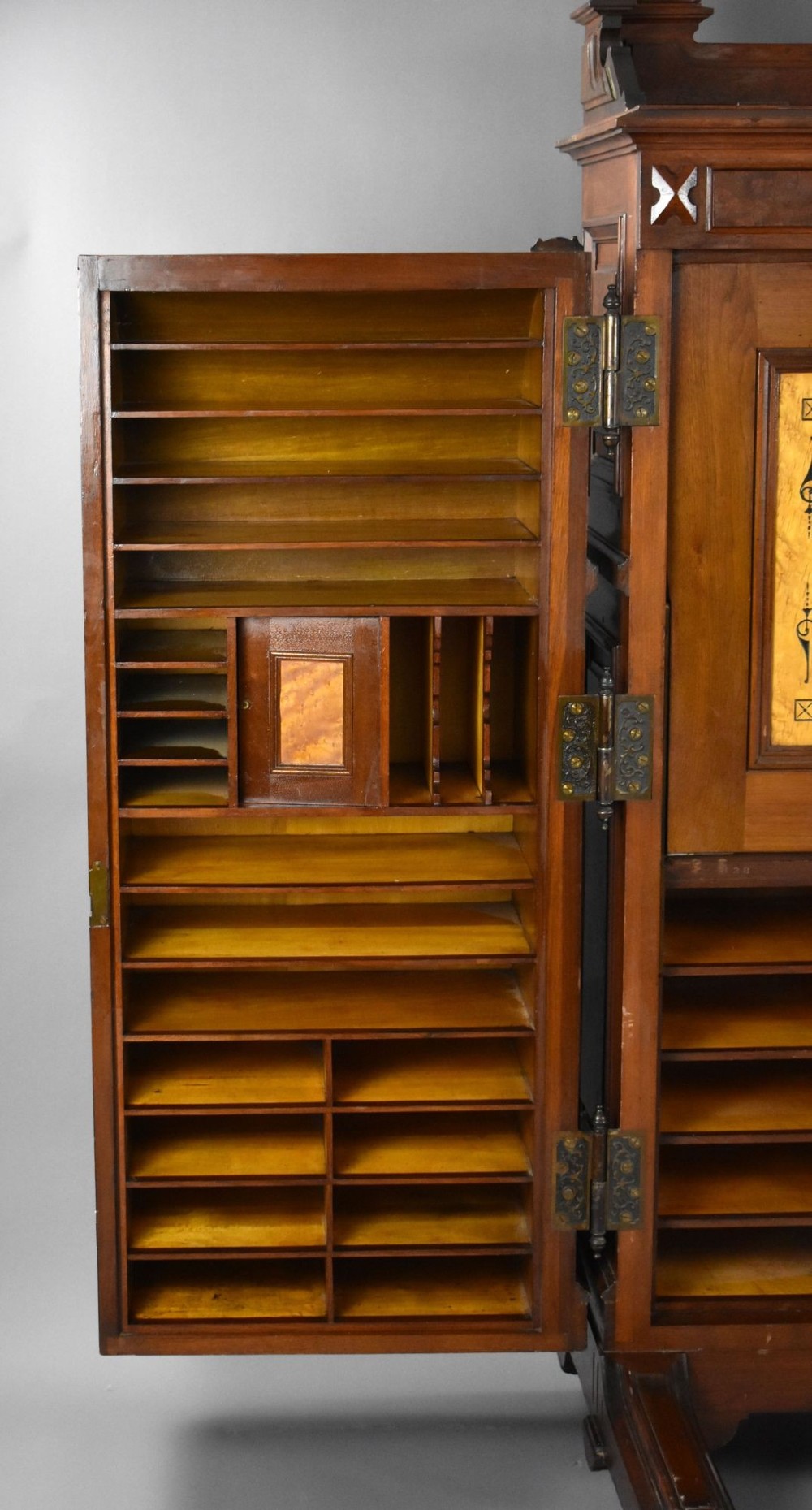 A Victorian walnut Wooton secretary desk featuring carved cresting, curved upper doors, panelling, brass mail slots, and carved feet on castors. View IV