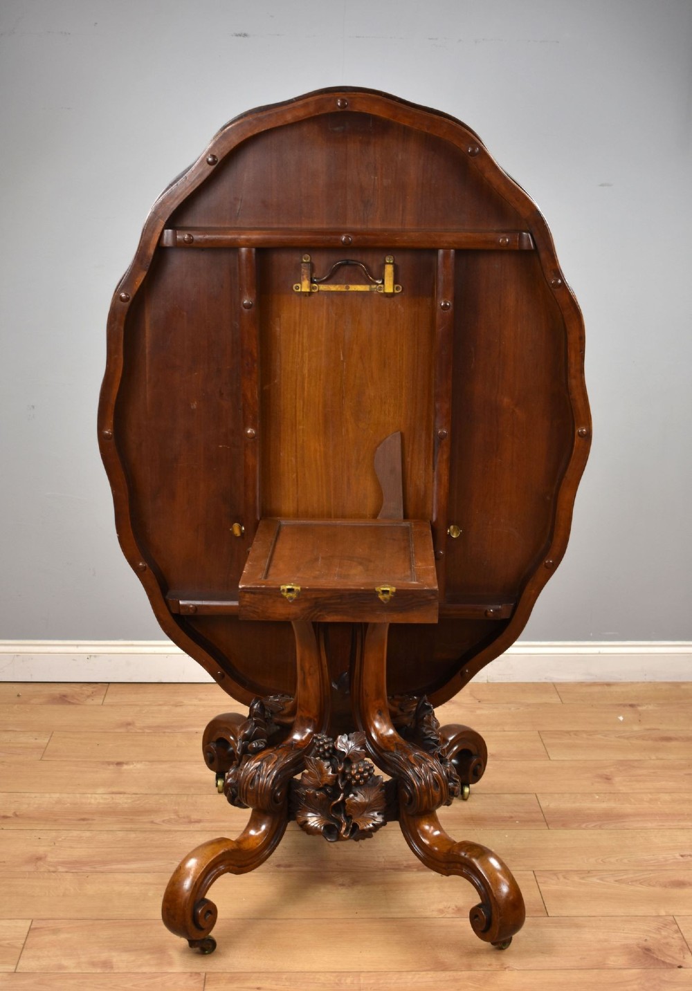 A Victorian tilt-top loo table shown vertically, featuring quarter-matched burr walnut veneer with a scalloped edge on carved cabriole legs. View III
