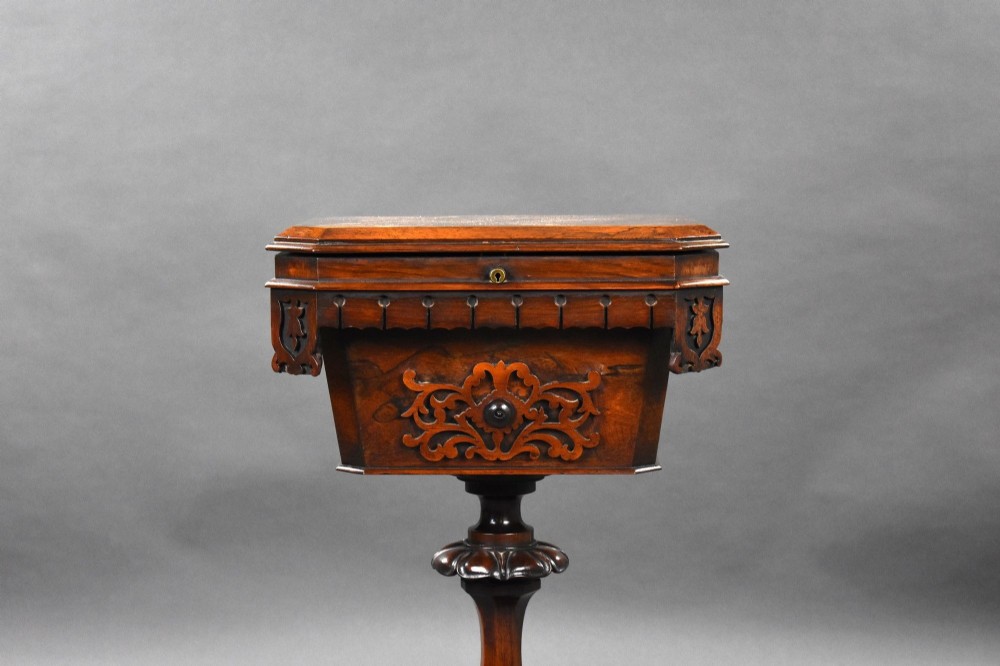 A William IV rosewood tea poy featuring a hinged lidded box top, carved openwork scrolls, a turned pedestal column, and a four-point base with scroll feet. View III