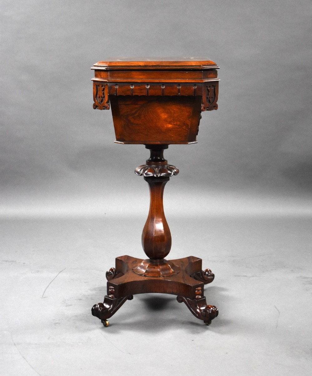 A William IV rosewood tea poy featuring a hinged lidded box top, carved openwork scrolls, a turned pedestal column, and a four-point base with scroll feet. View IV