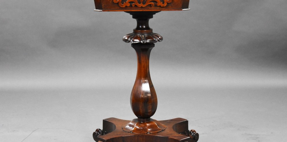 A William IV rosewood tea poy featuring a hinged lidded box top, carved openwork scrolls, a turned pedestal column, and a four-point base with scroll feet. View VIII