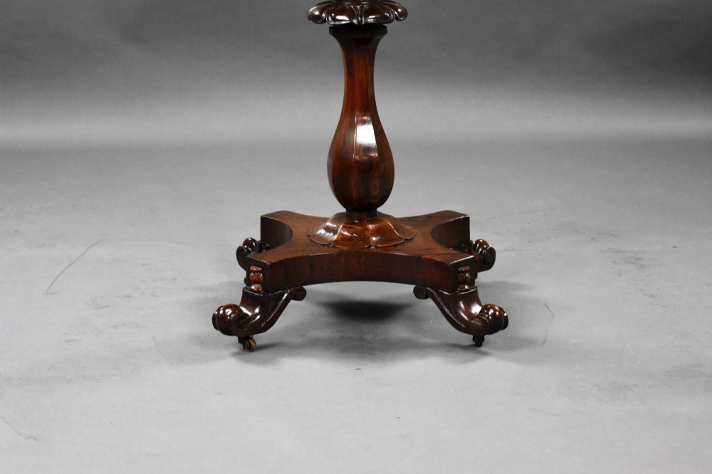 A William IV rosewood tea poy featuring a hinged lidded box top, carved openwork scrolls, a turned pedestal column, and a four-point base with scroll feet. View IX