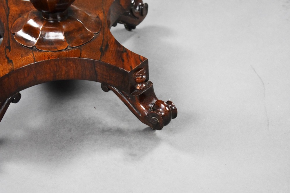 A William IV rosewood tea poy featuring a hinged lidded box top, carved openwork scrolls, a turned pedestal column, and a four-point base with scroll feet. View XII